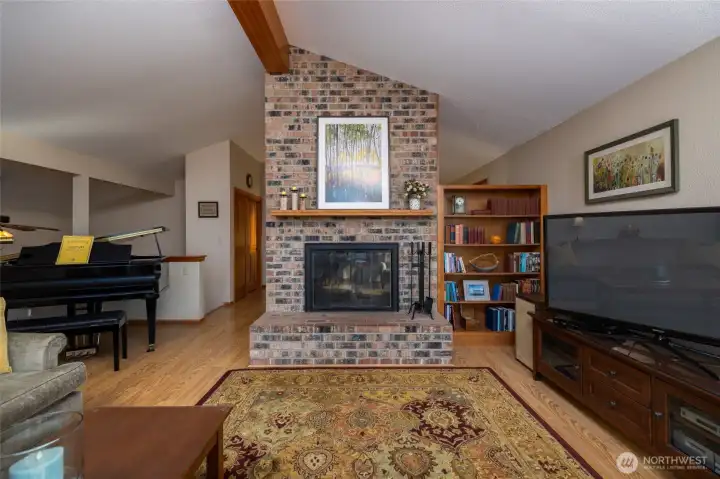 Living room with wood burning fireplace and vaulted ceilings.
