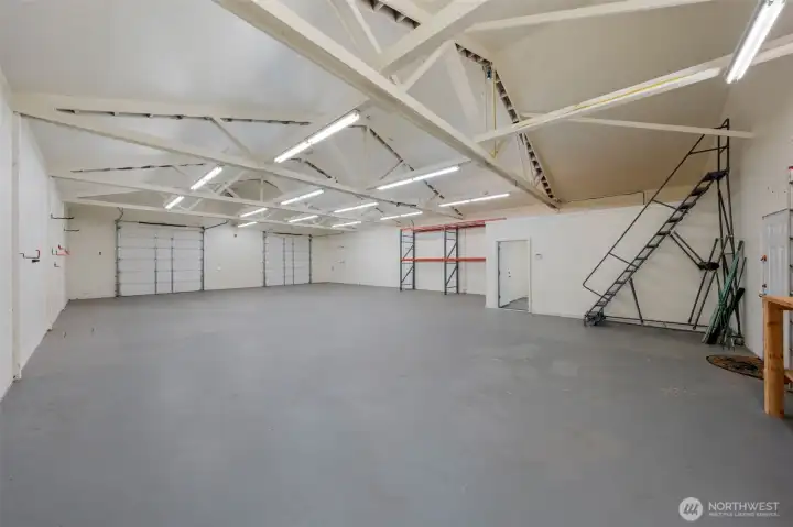 Shop interior showing double doors, industrial shelving, over-office storage and rolling ladder.