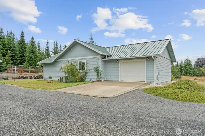 Exterior view highlighting attached garage, easy maintenance metal roof and clean design.