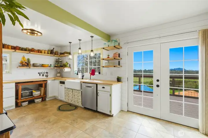 Farm style apron sink, open shelving, updated lighting and butcher block counter tops frame this country kitchen.