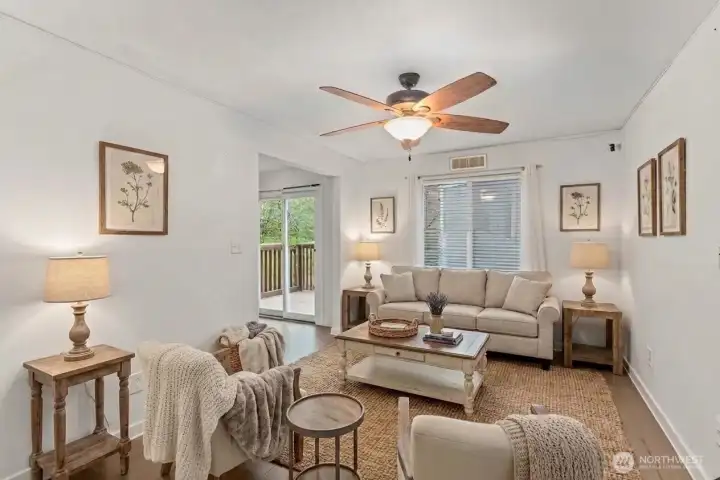 Living room with ceiling fan, view of backyard. (digitally staged)