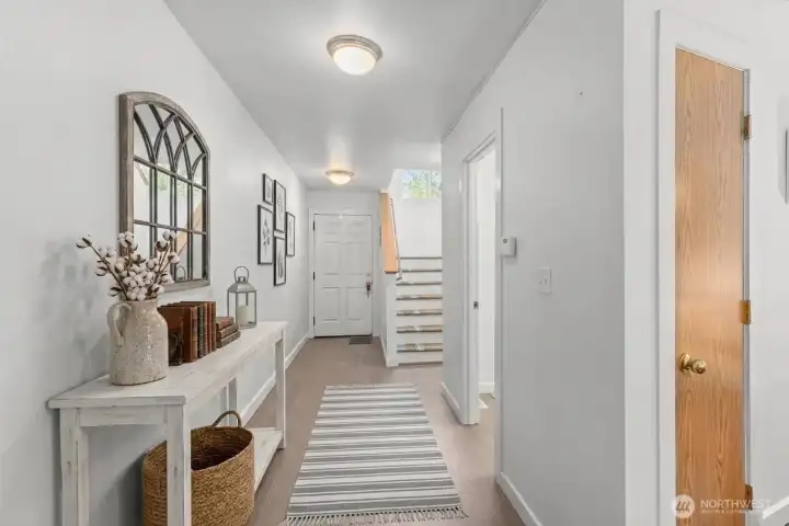 Hallway from front door, half bath on the right. (some decor digitally staged)