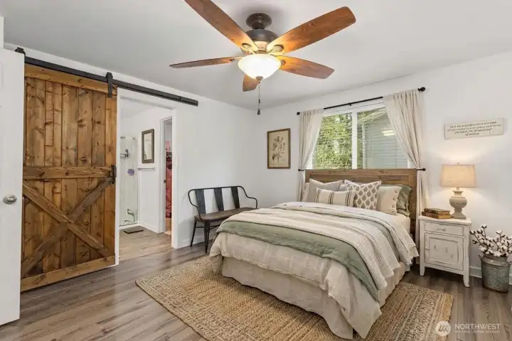 Primary bedroom with barn door, ceiling fan. (some decor digitally staged)
