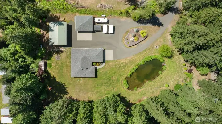 A true bird’s eye view of the full setting, showing how the home, pond, shops, outbuildings, yard, and trees all work together as one remarkable property.