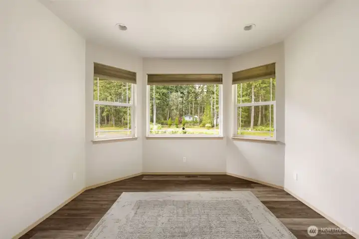 The front living room draws you toward the view, with curved windows overlooking the pond, driveway, and trees that give the home a comfortable sense of privacy.