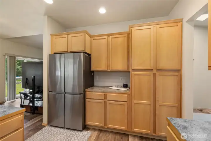 Thoughtful kitchen storage includes a wall of cabinetry, pantry space, a French door refrigerator, and a convenient counter nook with outlets that is ideal for coffee, small appliances, or a daily landing zone.