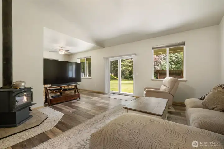 Large backyard windows and a sliding glass door bring the outdoors into the family room, connecting the warmth of the wood stove with easy access to the covered patio beyond.