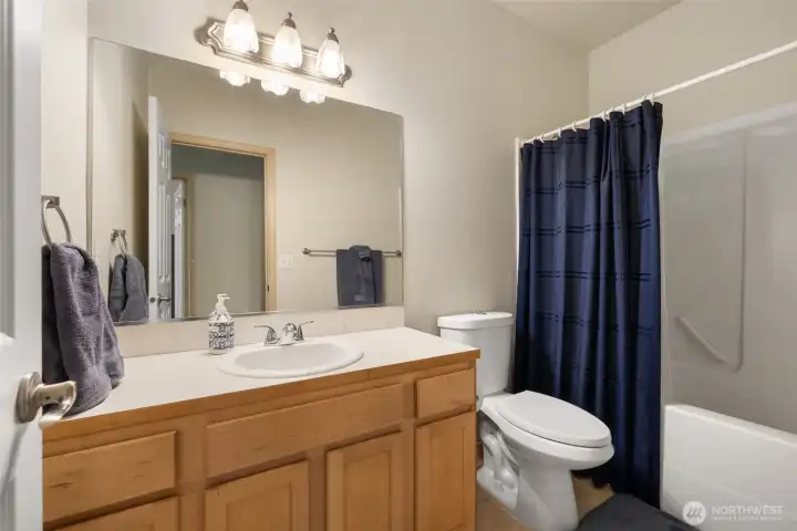 A clean, comfortable main bathroom with a full tub and shower offers everyday function in a simple, easy care space.