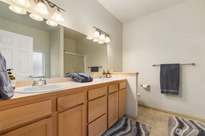 The primary bath offers generous counter space, dual sinks, extended cabinetry, and a large mirror that gives the room a bright, practical, easy to share layout.