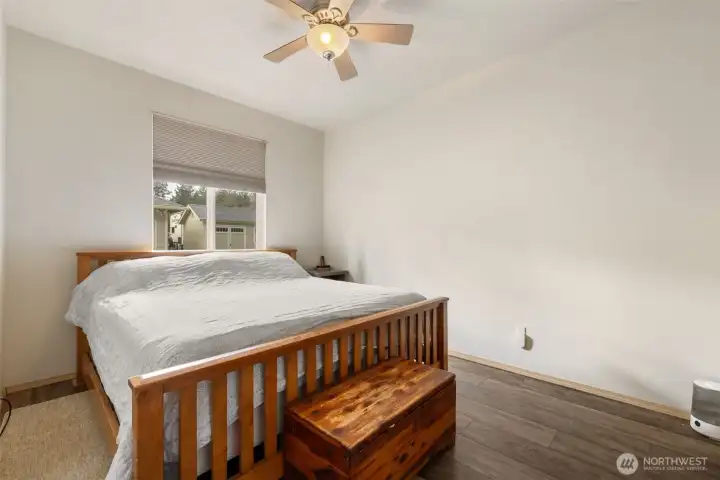 Bedroom two continues the home’s clean, cohesive feel with wood grain laminate floors, no carpet, and a view toward the shops and outbuildings that make this property so useful and versatile.