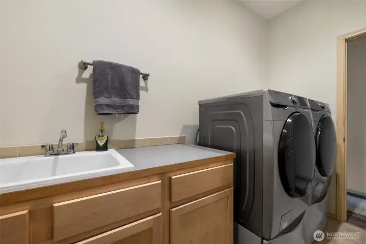 A practical utility room connects the garage to the main living areas, offering countertop space, cabinetry, drawers, a sink, and an easy spot for laundry, cleanup, and daily organization.