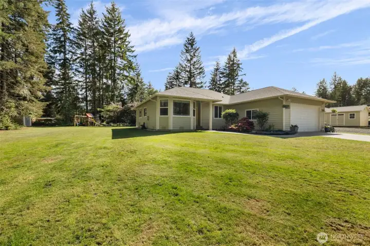One final look at a property that feels both expansive and deeply peaceful, with a wide green lawn, blue skies, mature trees, play space, and room to live, gather, create, and breathe.