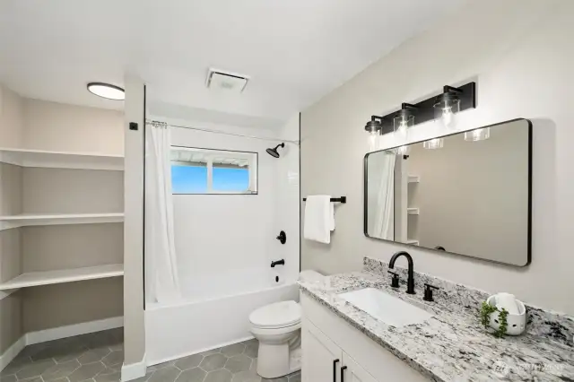 Lower level full bath with built-in linen storage—offering style and everyday practicality in one clean, cohesive space.