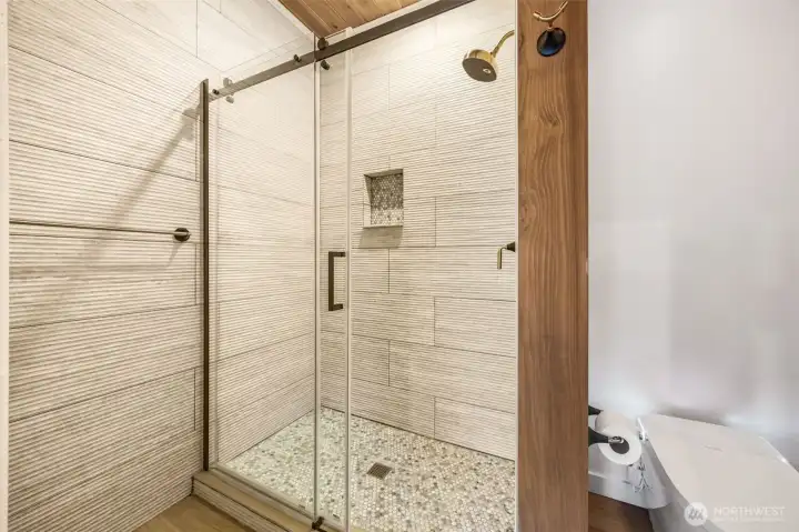 Walk in shower with tile walls.