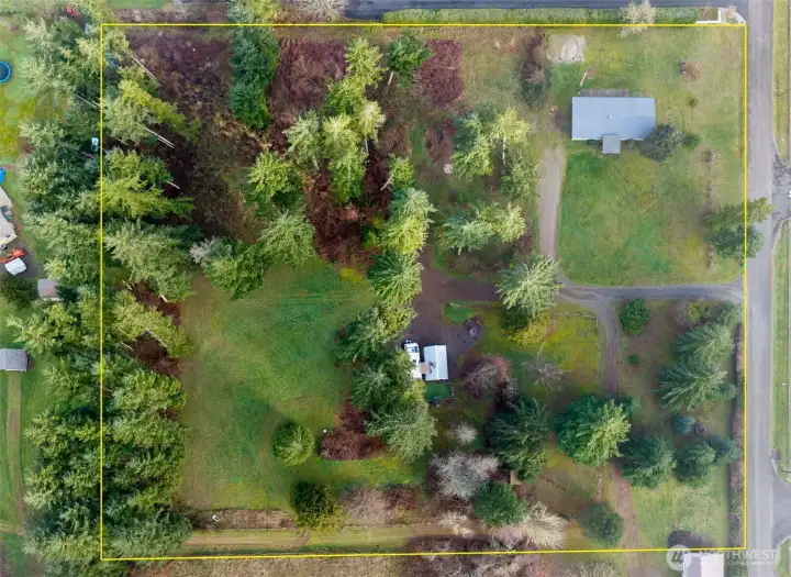 Aerial view of 3.68 acre property depicts mature tree, refurbished manufactured home location and additional RV site with 350 gal professionally installed holding tank, covered entertainment/outdoor living structure and fun outdoor space.