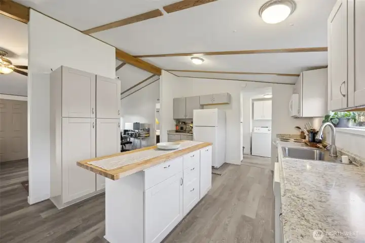 Kitchen redone in 2024.  New paint, cabinets, mostly new appliances.  All appliances stay.  New laminate countertops. Fresh and bright. Efficient layout.  In the background, convenient utility room with washer/dryer, storage and access to backyard.