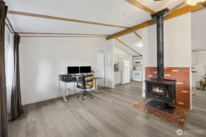 View to the left when entering the home. Functioning wood stove as second heat source.  Great room concept.
