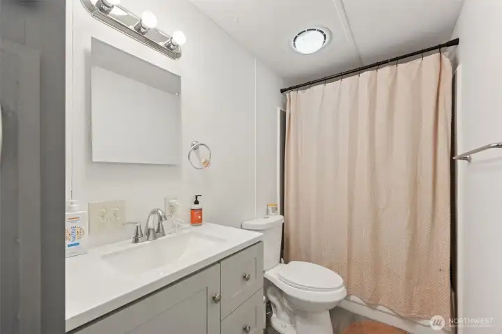 Second full bathroom; new flooring, fixtures, solid surface countertop, cabinetry; conveniently located near bedrooms two and three.