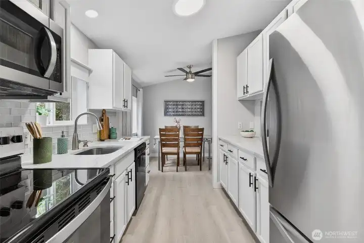White cabinetry and stainless steel appliances define this thoughtfully designed, easy-to-navigate galley-style kitchen.