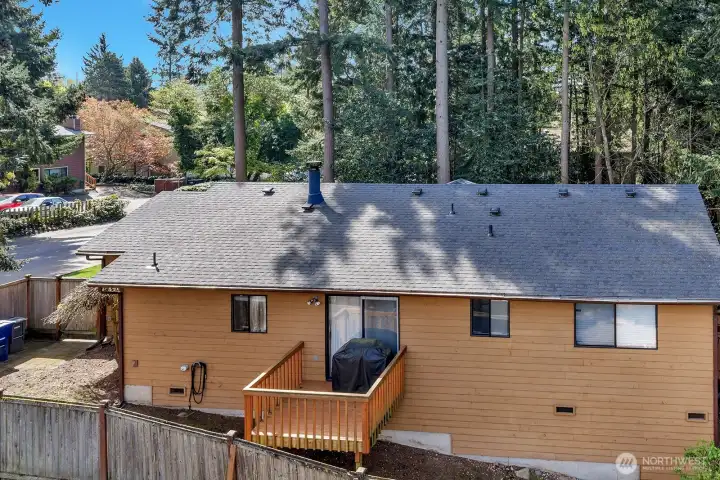View of the North side of the home. Private deck, accessible from the dining room area. Low maintenance yard. Gated entrance from driveway to this side yard. Home has new roof 2025-gutters cleaned and secured.