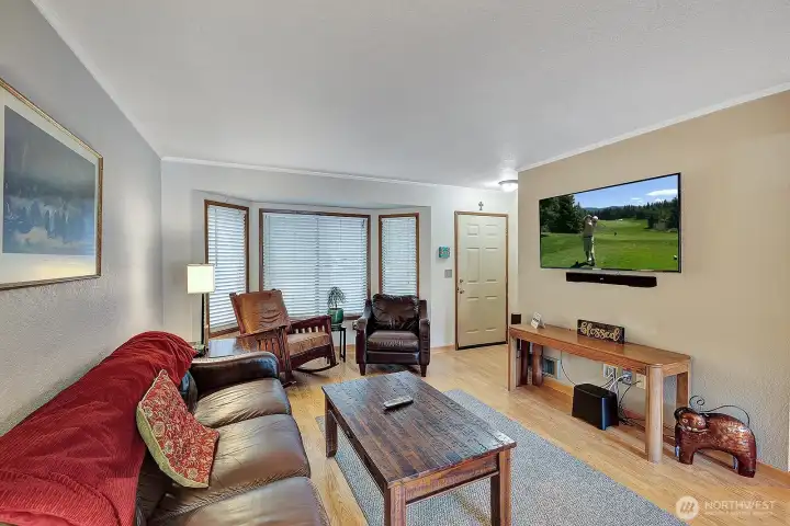 Front door & entry foyer, into the open and light living room with bay windows.  Neutral color scheme. Easy care laminate flooring. Room for sofa, love seat, recliner and additional furniture.