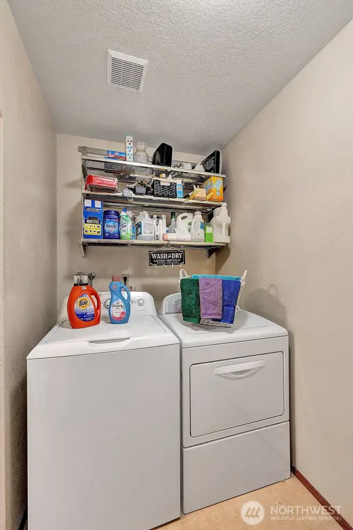 Utility room off the kitchen has access door to the double car garage. Full size washer and dryer and shelving for all your laundry supplies and necessities.
