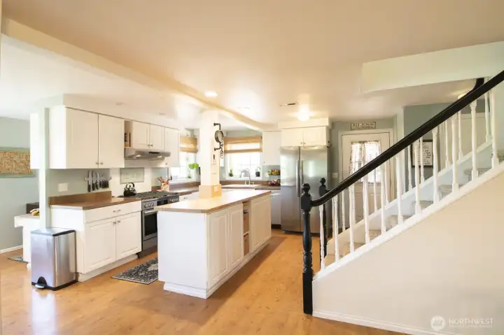Open-concept main level with kitchen island and staircase detail