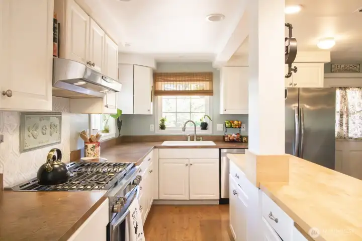Light filled kitchen with updated stove, refrigerator, dishwasher, and can lighting, plus ample counter space!