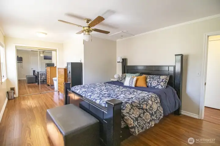 Spacious primary bedroom with hardwood floors, ceiling fan, and abundant natural light