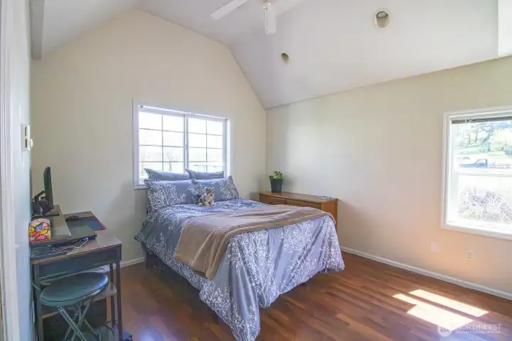 Bright bedroom with vaulted ceilings and warm natural light featuring a large closet with mirror doors
