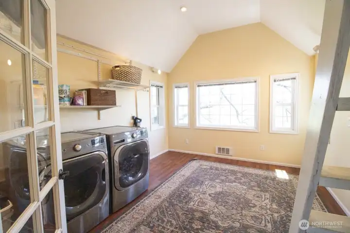 The french doors upstairs lead to a spacious laundry room with washer/dryer, utility sink, counter space, and lots of shelving