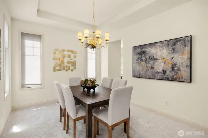 Elegant formal dining room showcasing tray ceilings and distinctive window cutouts, ideally situated near the kitchen.