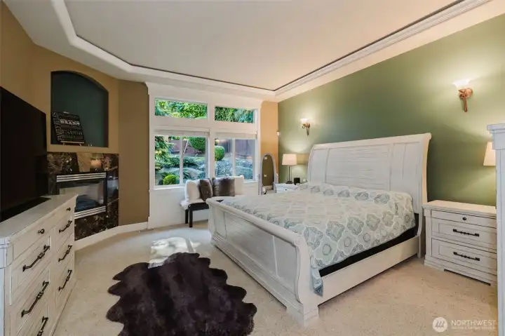 The main-floor primary suite offers the perfect blend of luxury and comfort, complete with a fireplace, elegant architectural details, and private garden views