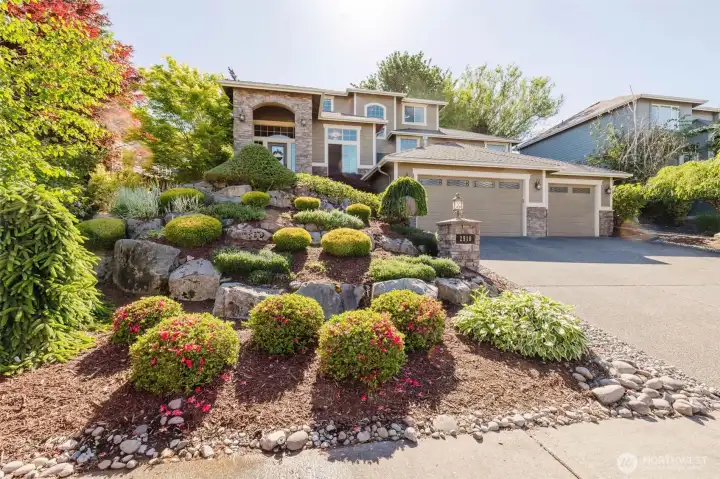 Perched above the street with mature landscaping and custom rockwork, this home showcases pride of ownership at every turn