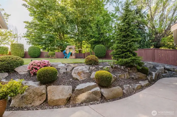 Professionally landscaped grounds showcase beautiful rock accents, mature plantings, and thoughtfully designed outdoor living spaces.