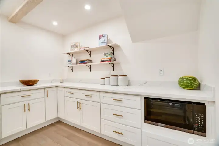 The walk-in pantry is a room unto itself — quartz counters, open shelving, and built-in microwave. The walk-in pantry is a room unto itself — quartz counters, open shelving, and built-in microwave.