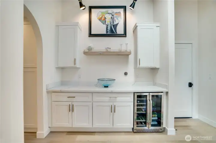 Dedicated wine and beverage station with dual-zone refrigerator, custom cabinetry, and floating shelf — the detail that separates this home from everything else at the price point. Dedicated wine and beverage station with dual-zone refrigerator, custom cabinetry, and floating shelf — the detail that separates this home from everything else at the price point.