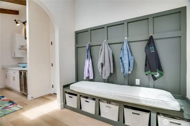 Custom mudroom with built-in bench seating, storage cubbies, hooks, and designer board and batten — practical luxury from the moment you walk in from the garage. Custom mudroom with built-in bench seating, storage cubbies, hooks, and designer board and batten — practical luxury from the moment you walk in from the garage.
