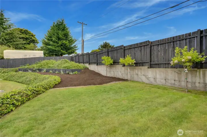 The fully fenced backyard stretches deep — lawn & terraced planting beds. The fully fenced backyard stretches deep — lawn & terraced planting beds.