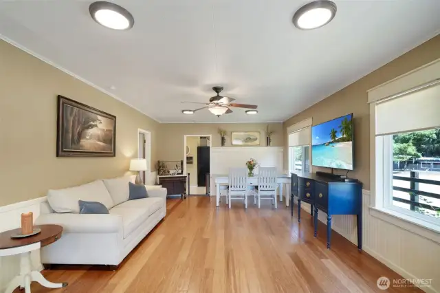 Living room with ceiling fan, gas fireplace on right, bedrooms and bath on left, kitchen entry straight ahead