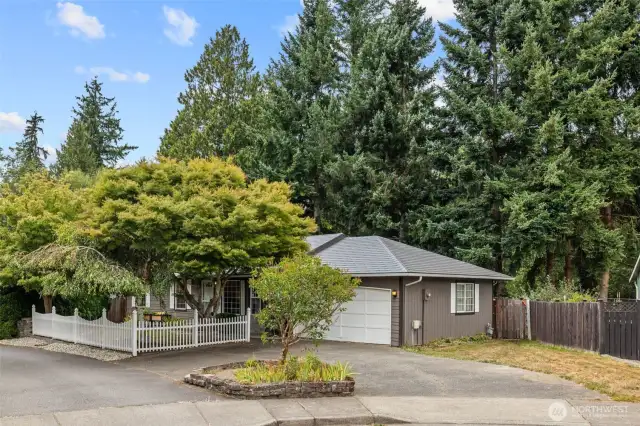 An inviting touch with white picket fencing, sidewalk up, and mature landscape all to greet your guests.