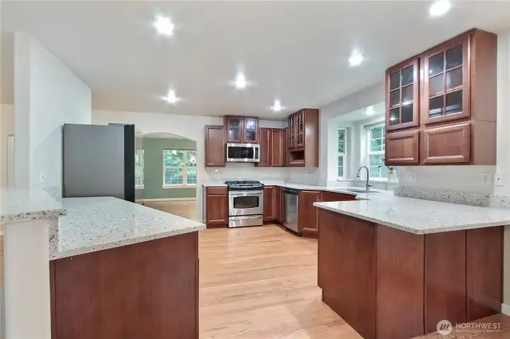 Kitchen view towards your formal dining room, love all the granite! Plenty of counter space, included stainless steel appliances and custom cabinetry - a chef's delight!