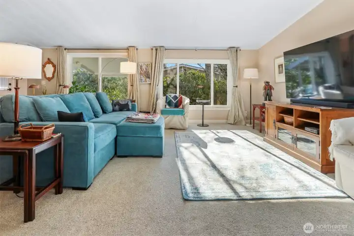 Formal living room with vaulted ceilings, sliding door to front patio and picture window overlooking the community greenbelt and trail