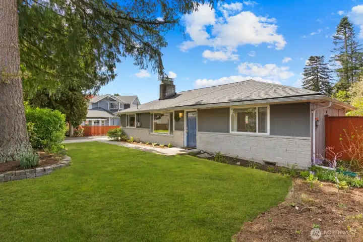 Front exterior with mature landscaping, covered entry, and attached garage. Situated in a quiet residential setting with a well maintained yard and driveway.