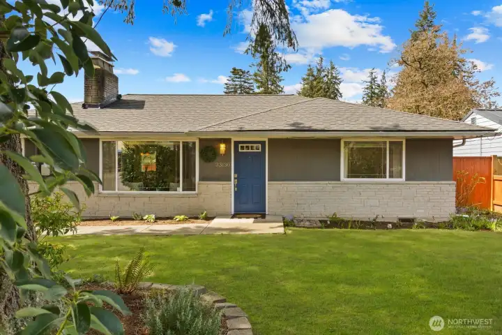 Front exterior with mature landscaping, covered entry, and attached garage. Situated in a quiet residential setting with a well maintained yard and driveway.