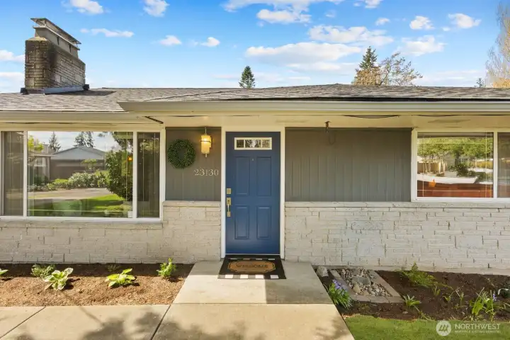 Front exterior with mature landscaping, covered entry, and attached garage. Situated in a quiet residential setting with a well maintained yard and driveway.