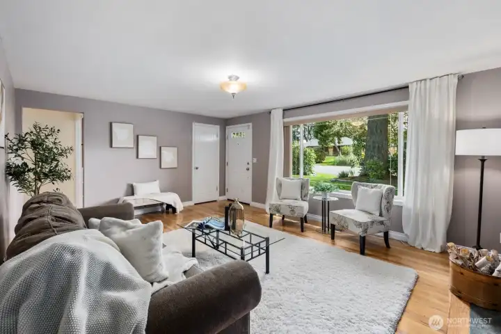 Living room with large windows, fireplace, and accent wall. Natural light and open layout create a comfortable main gathering space.