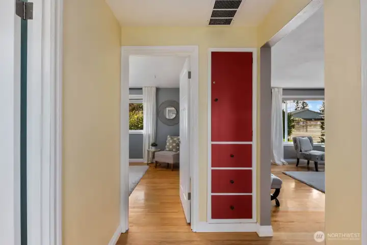 Hallway with hardwood floors, multiple room access, and built in storage cabinetry for added functionality. The central layout provides efficient flow between living areas and bedrooms while maximizing everyday organization.
