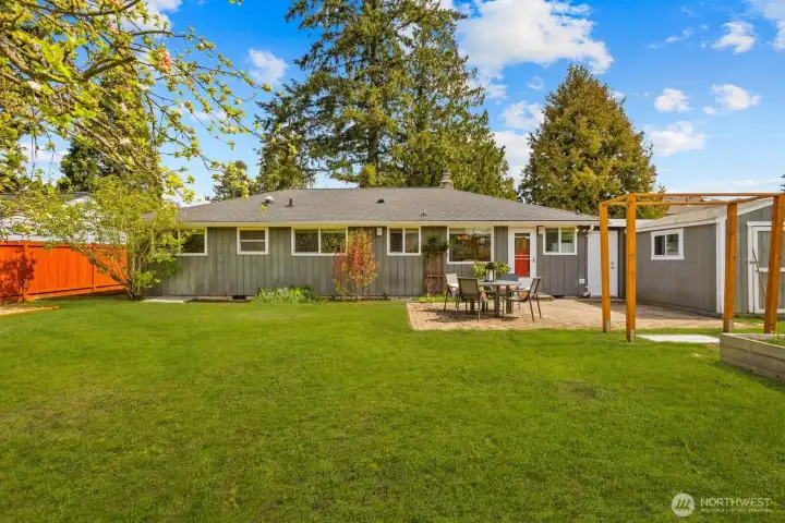 Large backyard with lawn, raised garden beds, and detached structure for storage or additional use. Outdoor space supports a variety of activities.