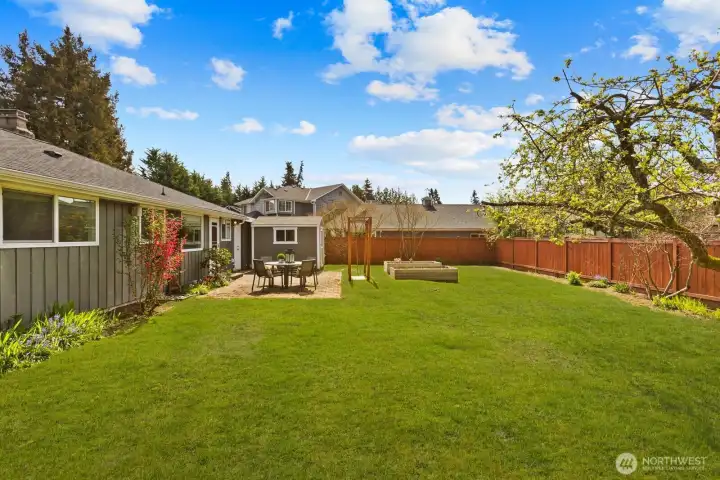 Large backyard with lawn, raised garden beds, and detached structure for storage or additional use. Outdoor space supports a variety of activities.